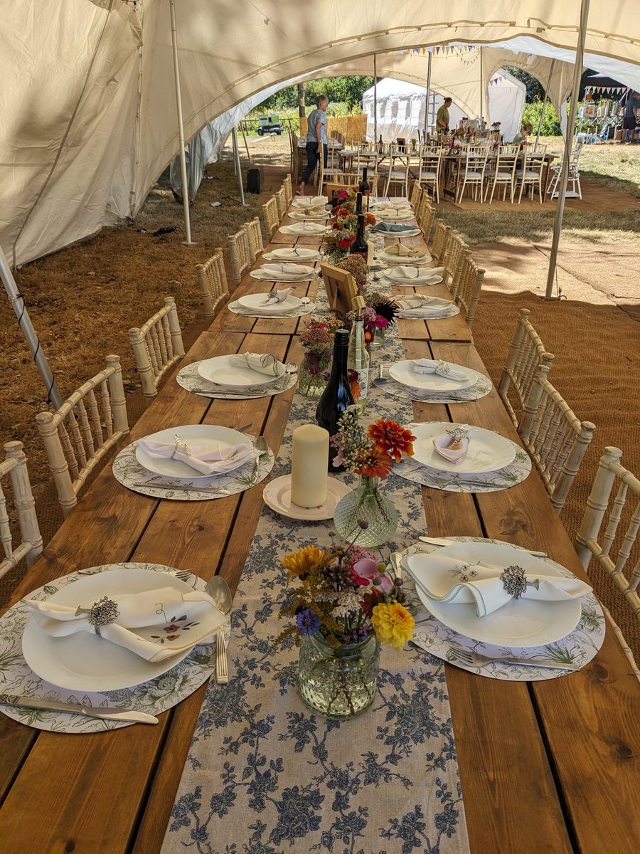 A table laid with plates, napkins, candles and jars of garden flowers
