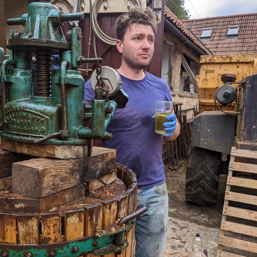 Tasting a glass of fresh juice beside the old cast-iron basket press